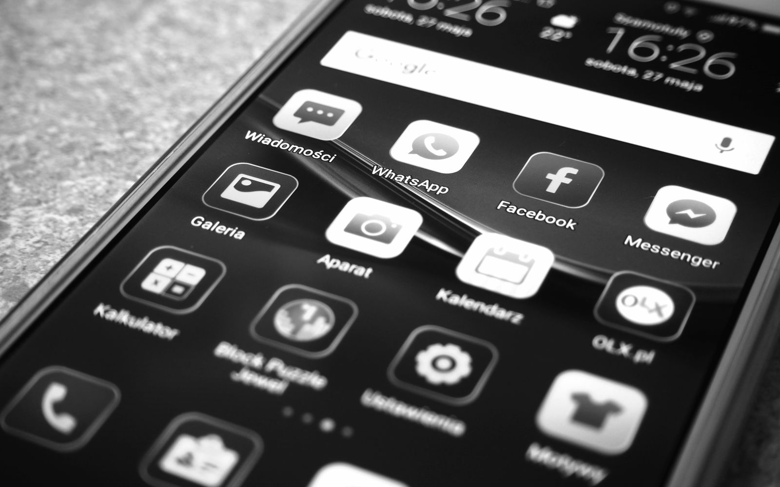 Foto em preto e branco de celular com ícones de Facebook e WhatsApp
