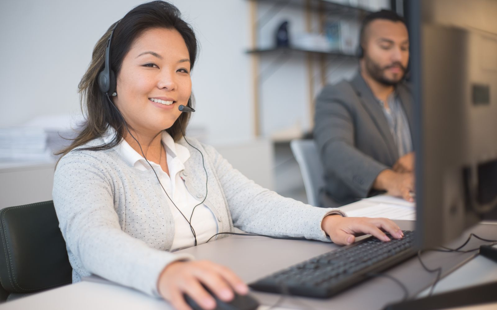 Dois atendentes de headset trabalhando em escritório moderno
