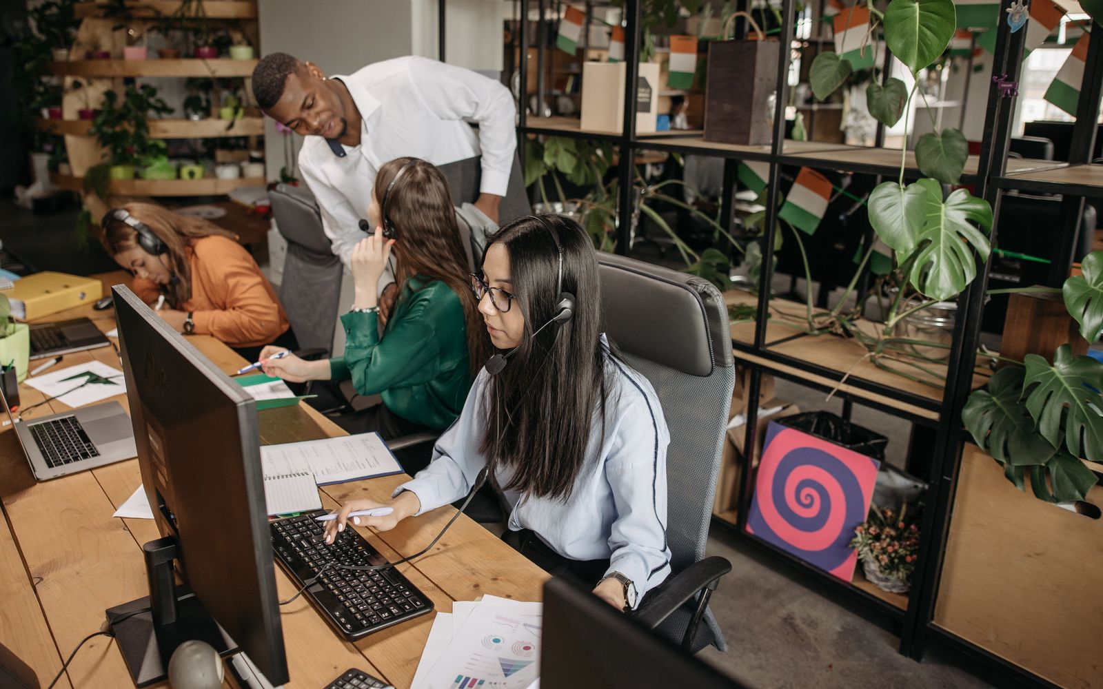 Equipe diversa trabalhando junto em computadores num escritório moderno