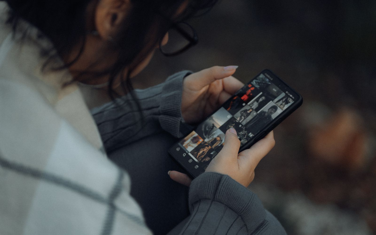 Jovem mulher navegando em uma galeria de fotos no smartphone ao ar livre, mostrando tecnologia e estilo de vida