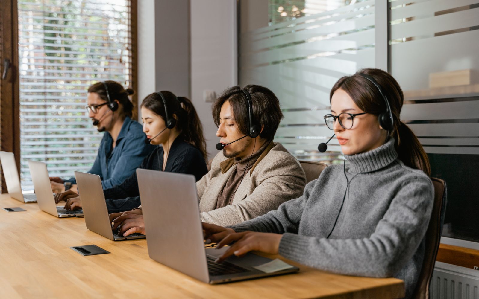 Uma equipe diversa de centro de atendimento utiliza laptops e fones de ouvido para prestar suporte ao cliente de forma eficiente