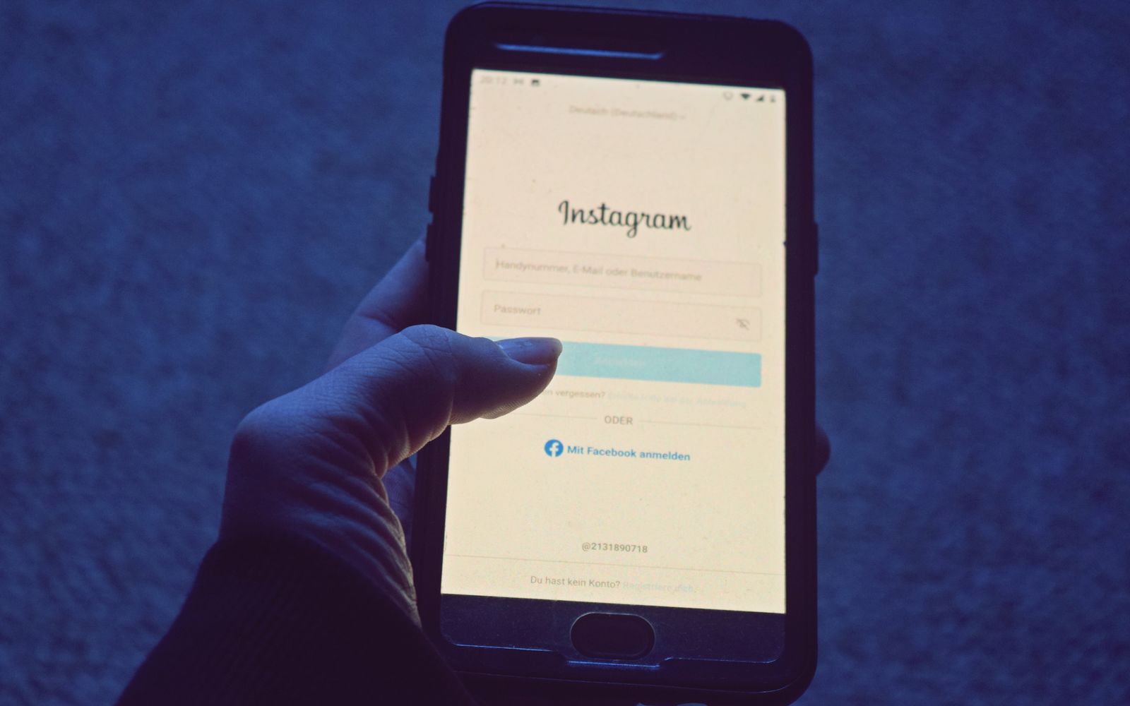 Foto em close de uma mão segurando um smartphone exibindo a tela de login do Instagram