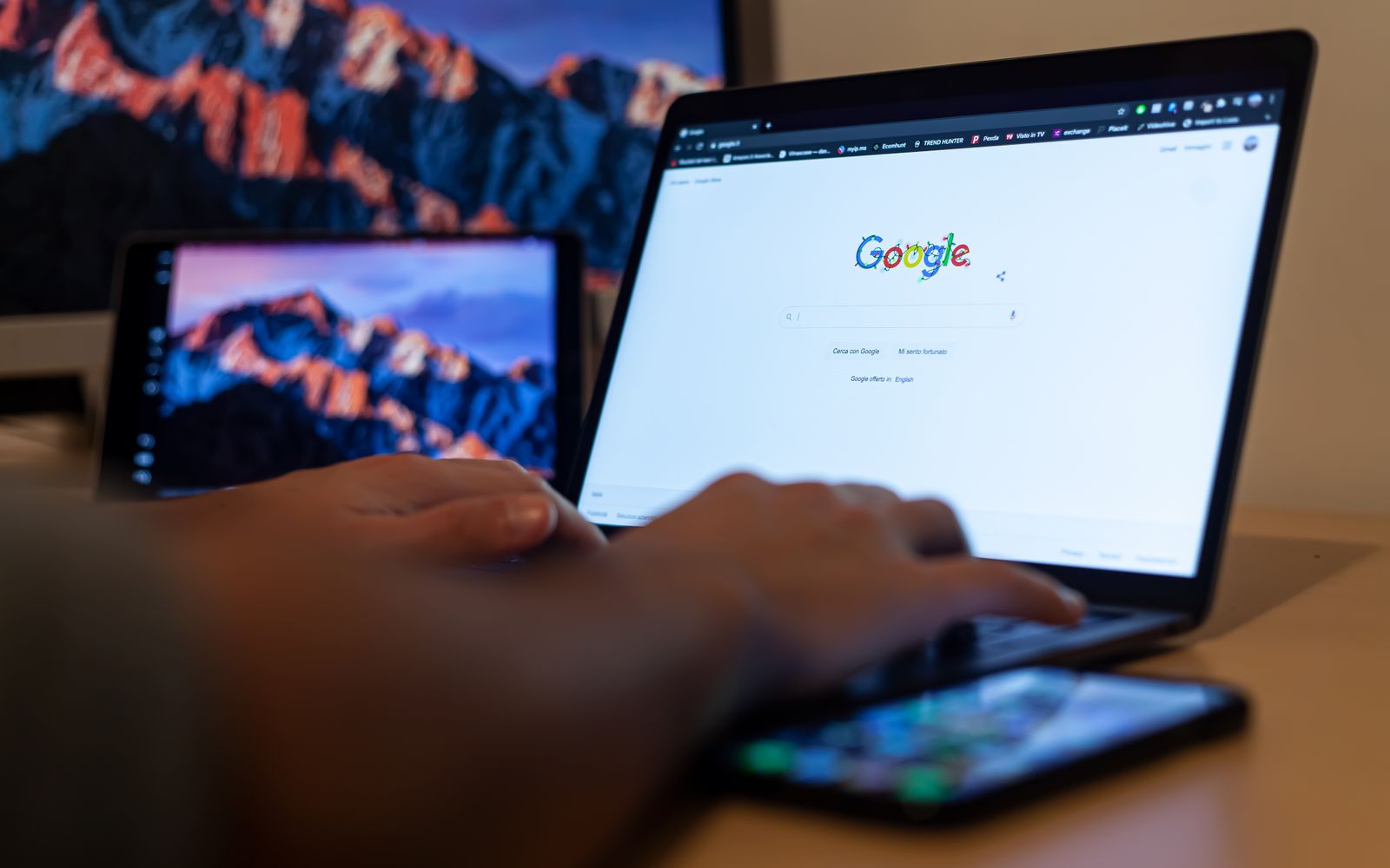 Mãos digitando em notebook com o Google aberto, em trabalho remoto