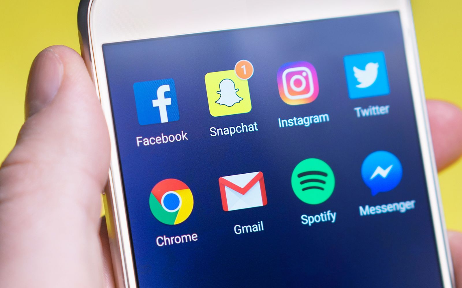 Mão segurando celular com aplicativos de mensagem e redes sociais