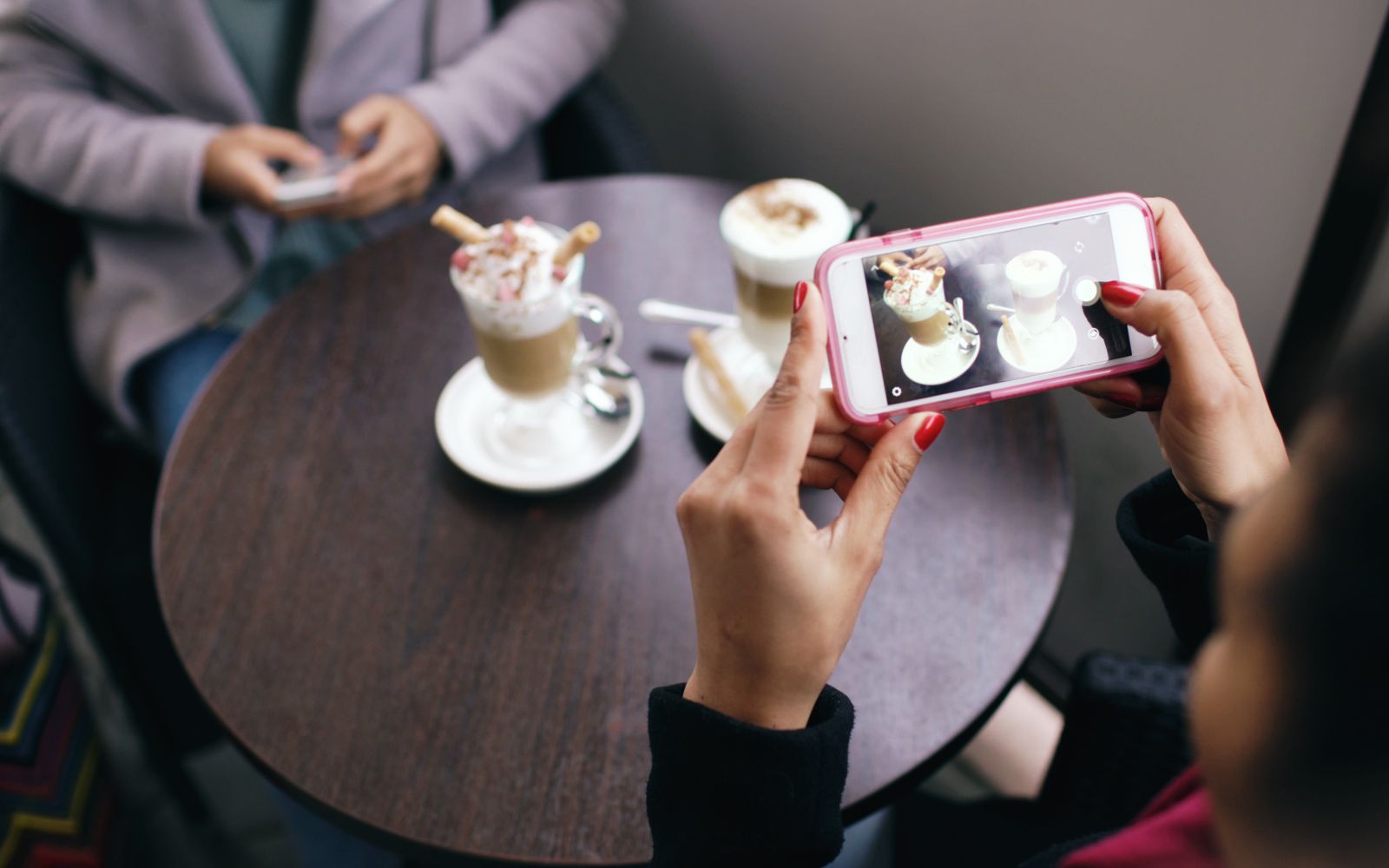 Duas mulheres fotografando o café com os celulares