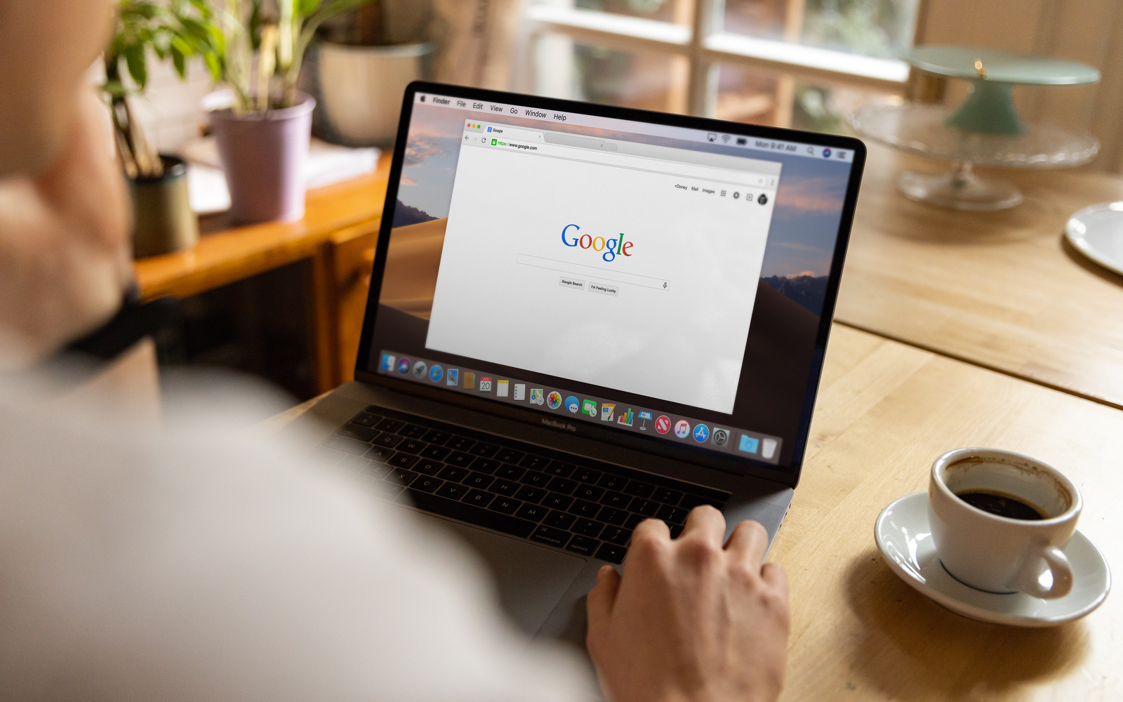 Adulto usando notebook em mesa de madeira, com o Google aberto e um café