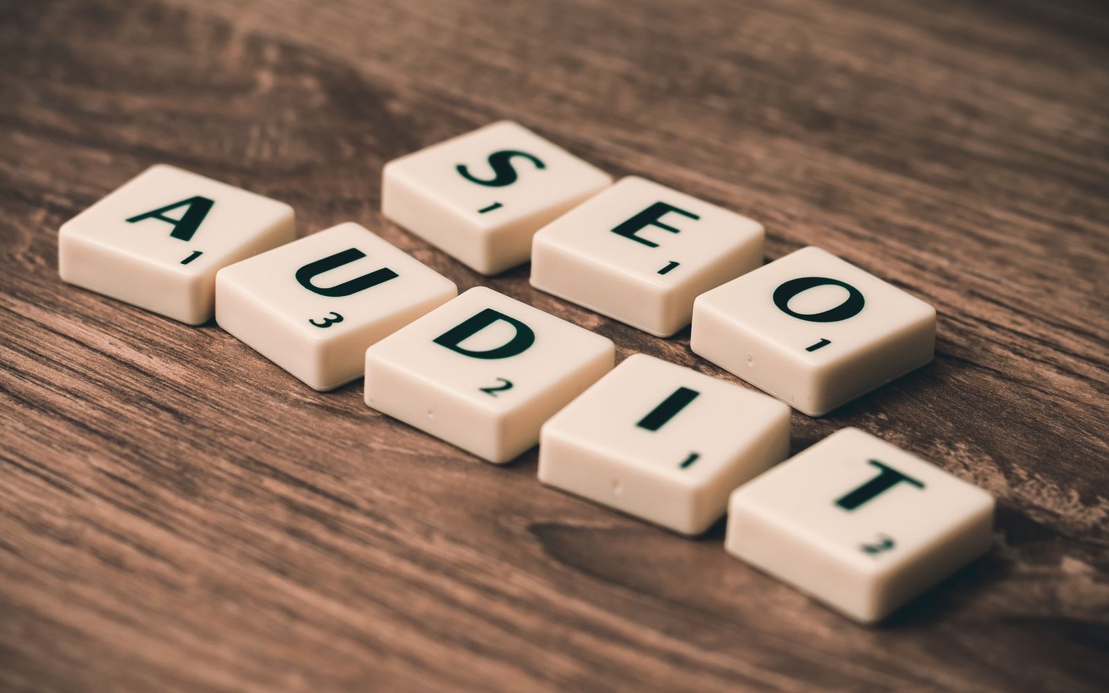 Peças de jogo formando a expressão SEO Audit sobre madeira