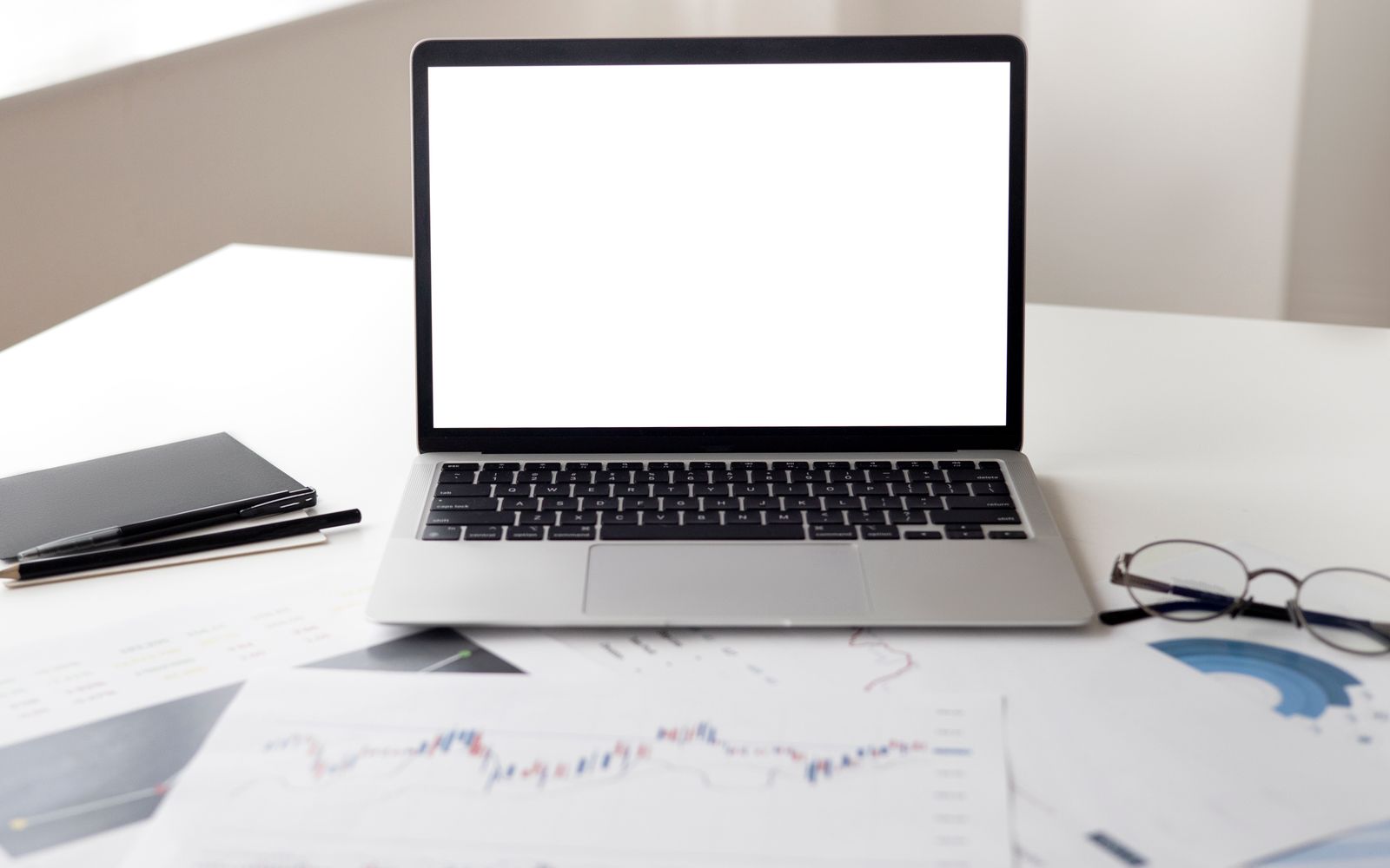 Notebook aberto sobre a mesa junto de documentos financeiros