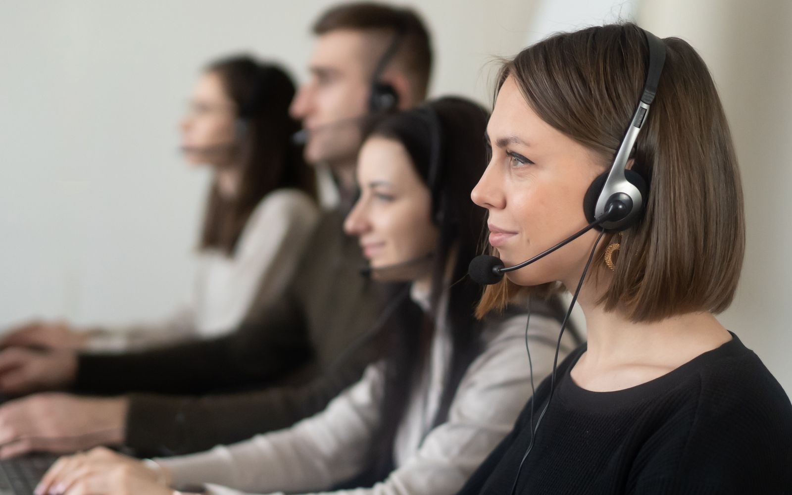Colegas de trabalho com fones e microfone usando notebooks em ambiente claro
