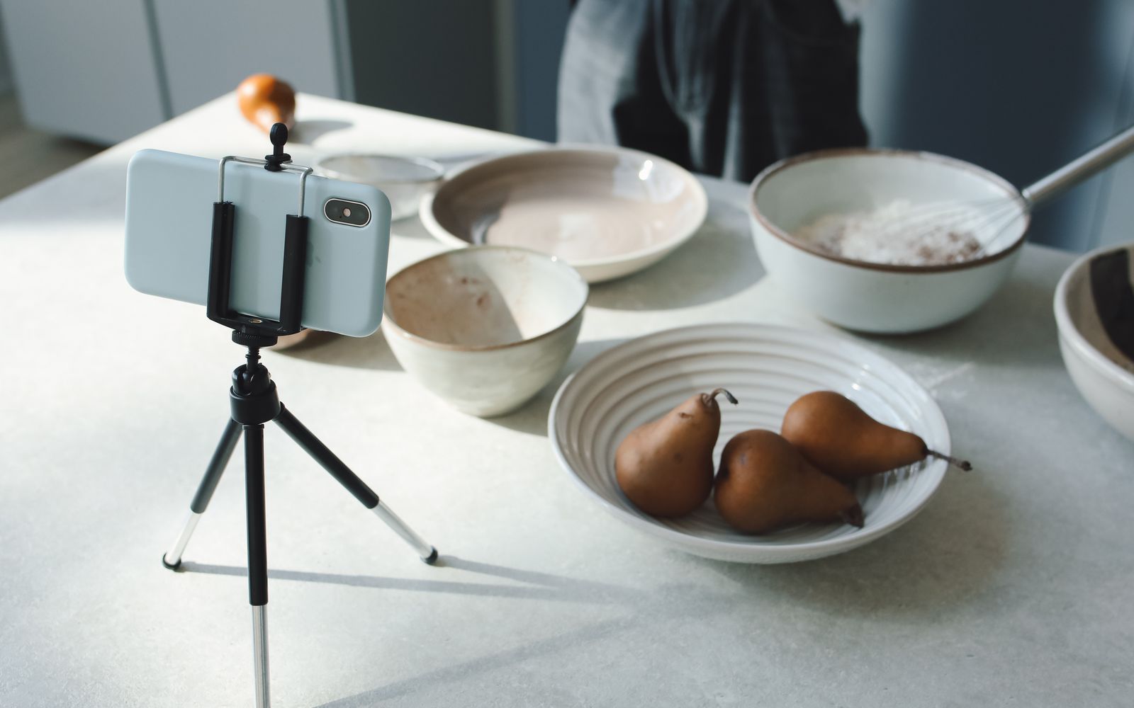 Cozinha com preparo de receita e celular montado em tripé