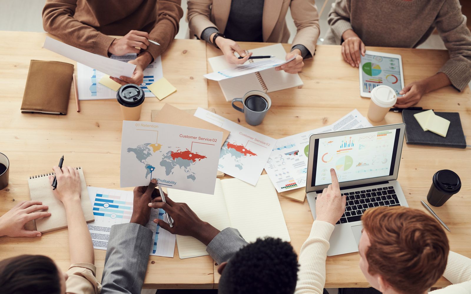 Equipe diversa participando de uma reunião colaborativa com gráficos e laptops