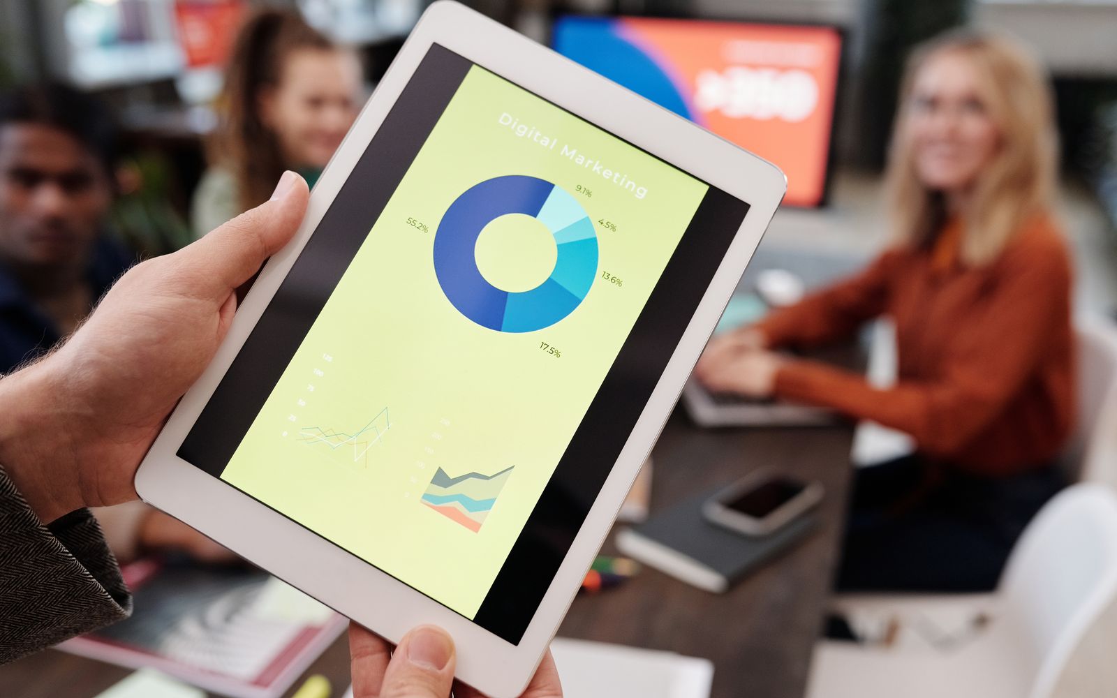 Equipe analisando métricas de marketing digital em um tablet durante reunião