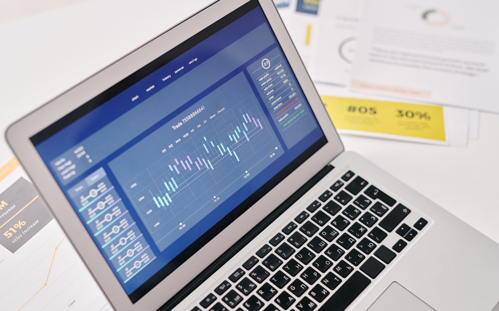 Notebook aberto com gráficos e relatórios ao lado de documentos