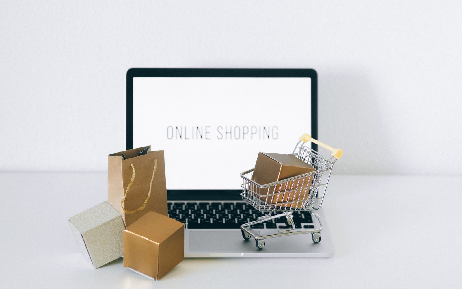 Notebook com uma loja virtual aberta, ao lado de caixas e um carrinho