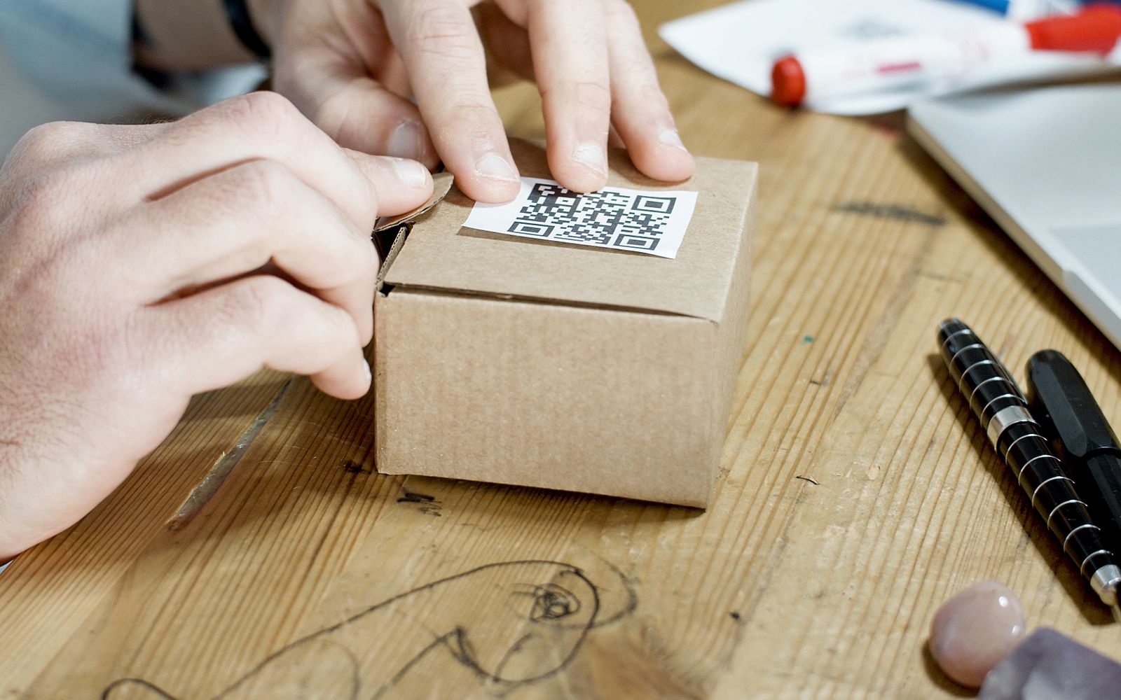 Mãos embalando uma caixa com QR code