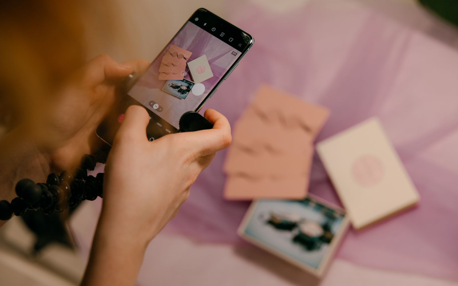 Mãos fotografando papelaria rosa com o celular