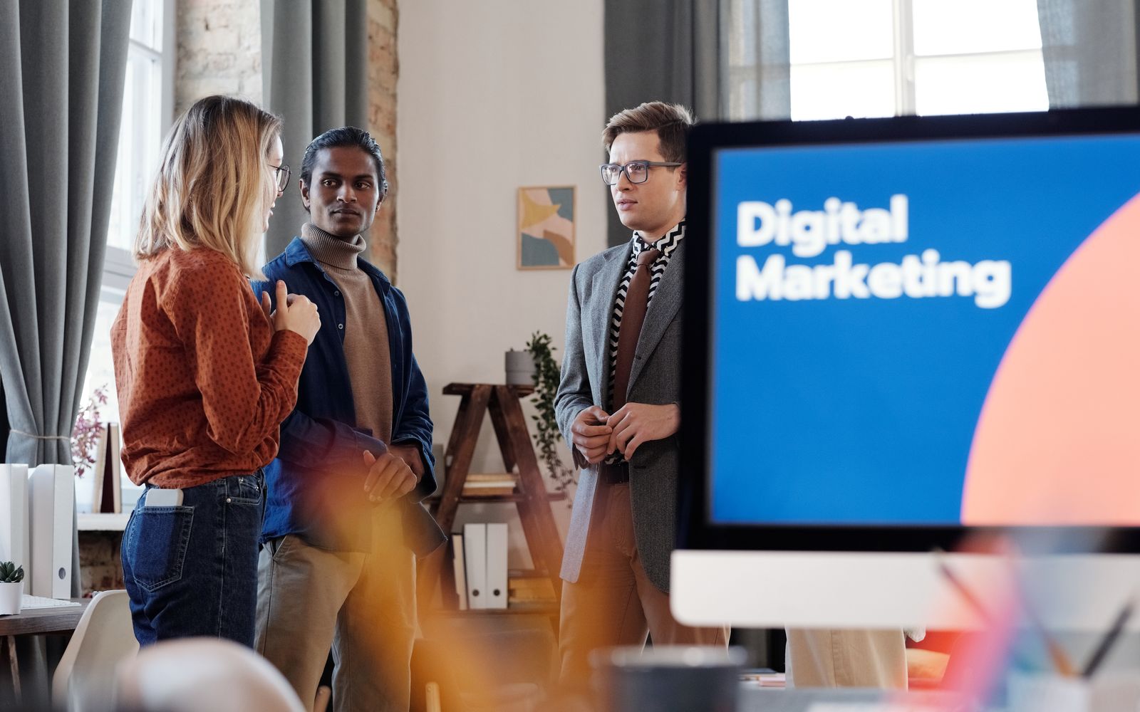 Grupo de colegas discutindo estratégias de marketing digital em um ambiente de escritório