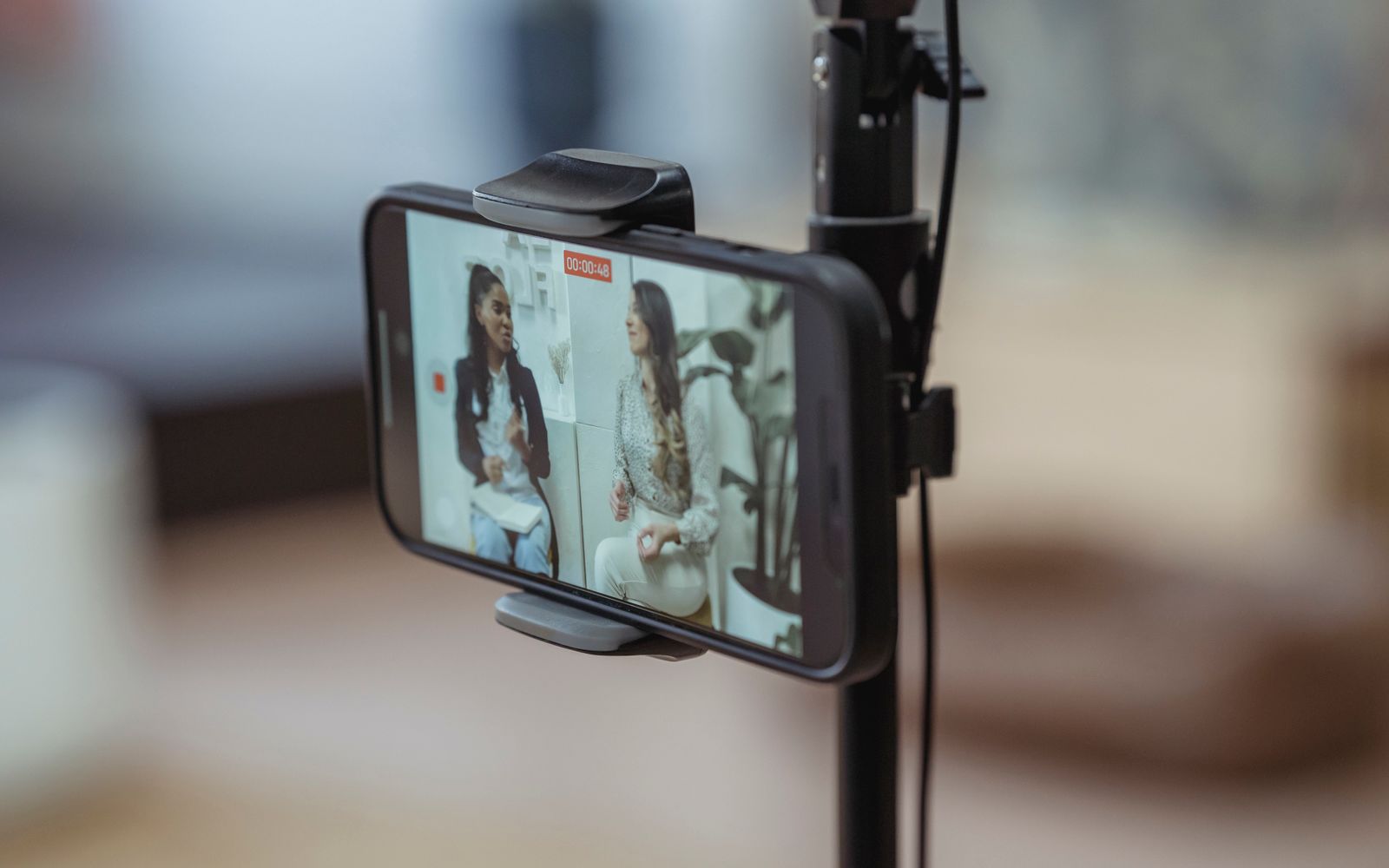 Celular em tripé gravando duas mulheres em conversa
