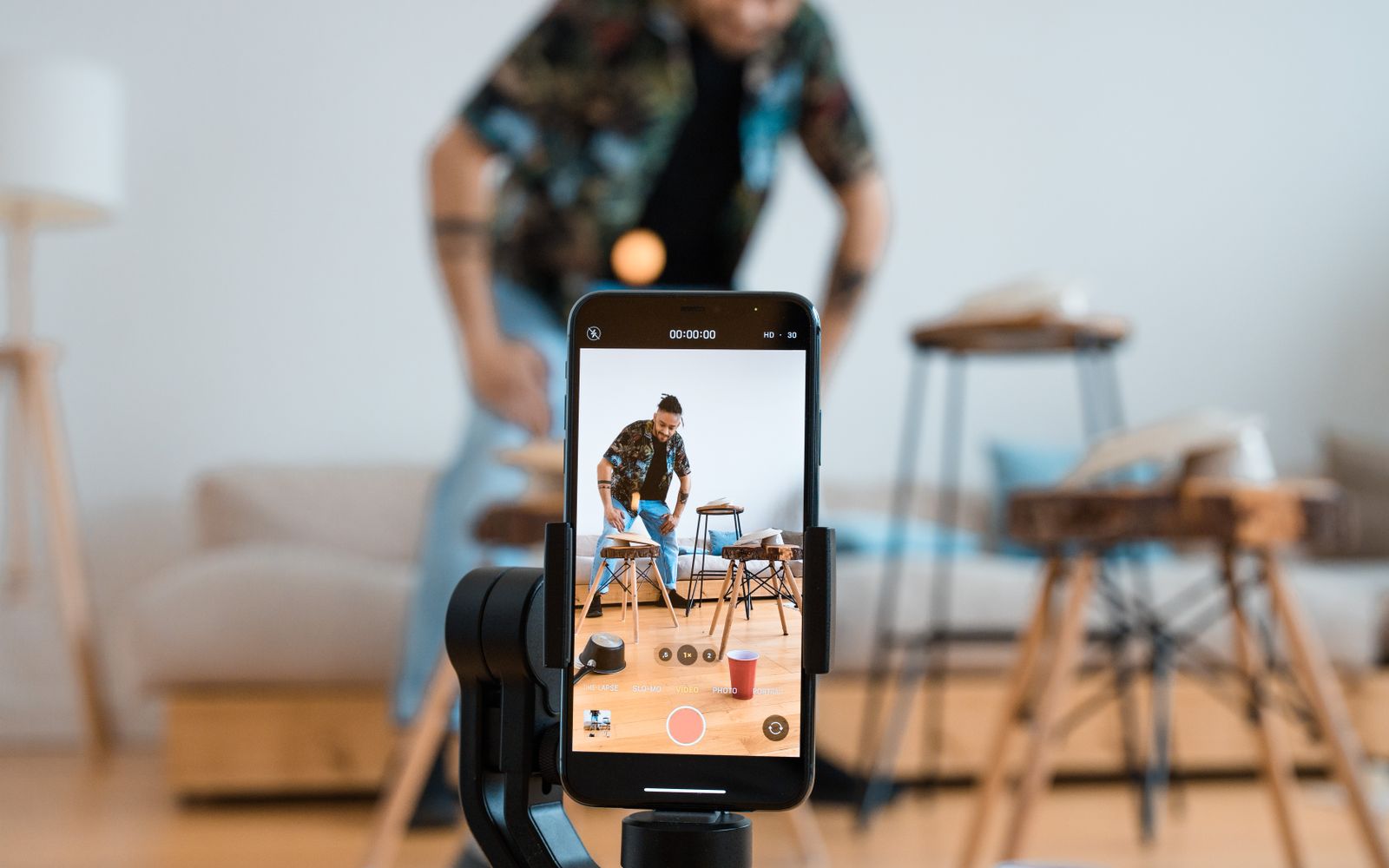 Homem gravando vídeo com celular em tripé na sala de casa