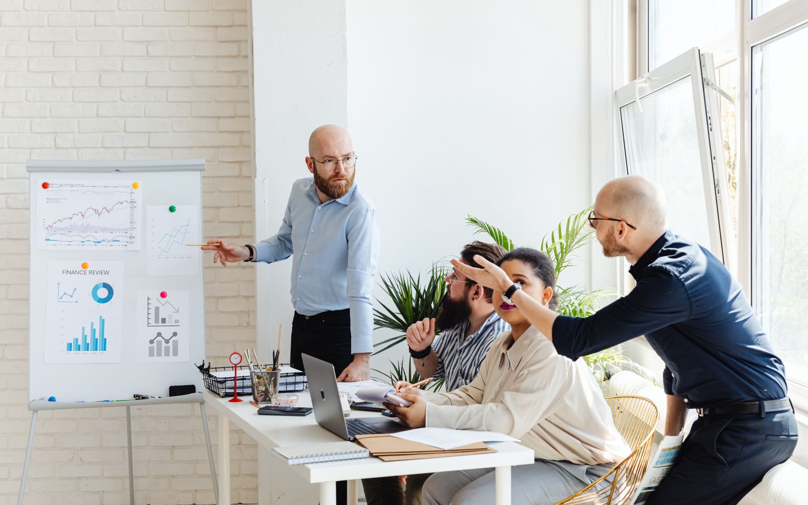 Um grupo de profissionais participando de uma reunião de negócios, discutindo gráficos financeiros em um quadro-branco