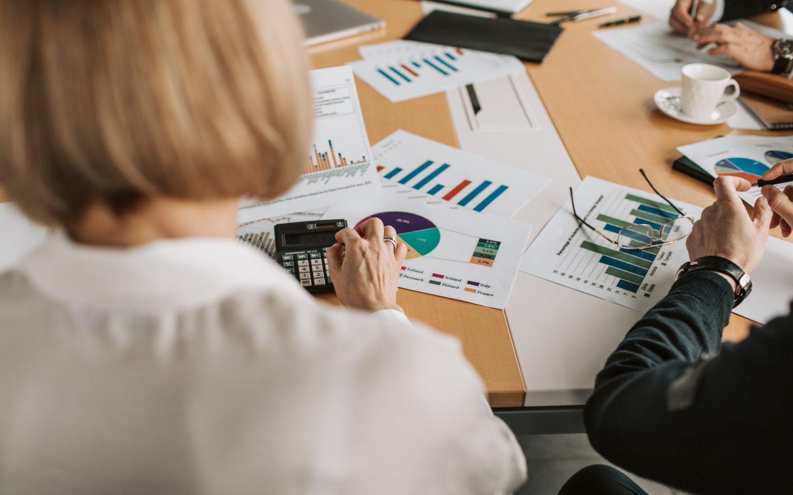 Vista superior de profissionais discutindo gráficos financeiros e usando calculadoras em um ambiente de escritório