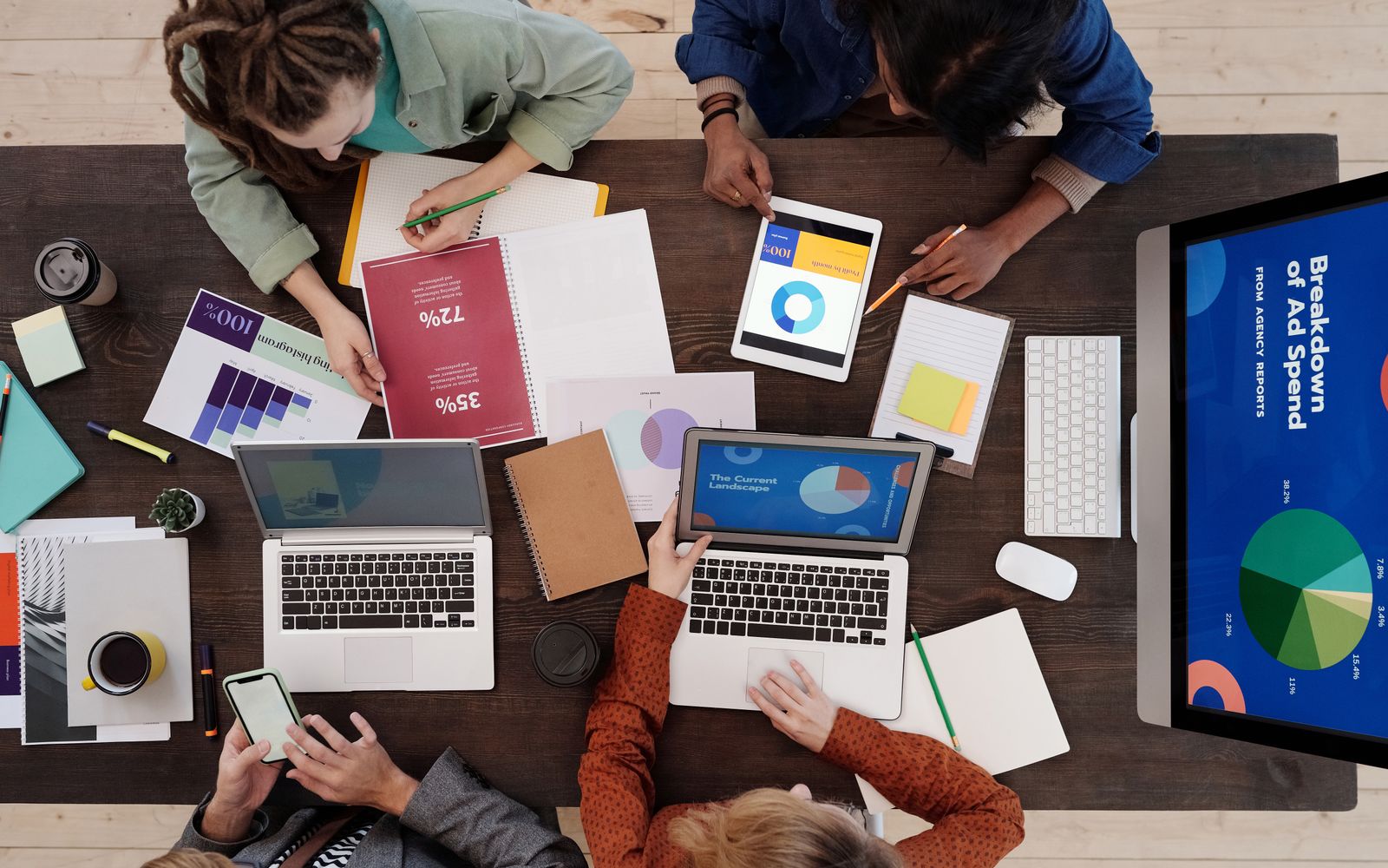 Uma equipe diversa colaborando em estratégias de marketing digital em uma mesa, usando laptops e tablets