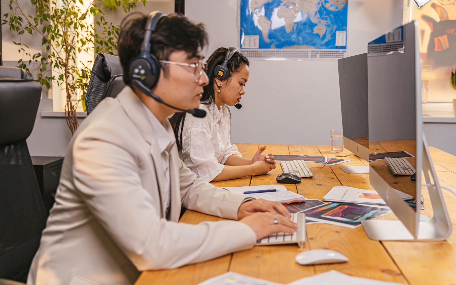 Atendentes de call center trabalhando em computadores com headsets em um escritório moderno