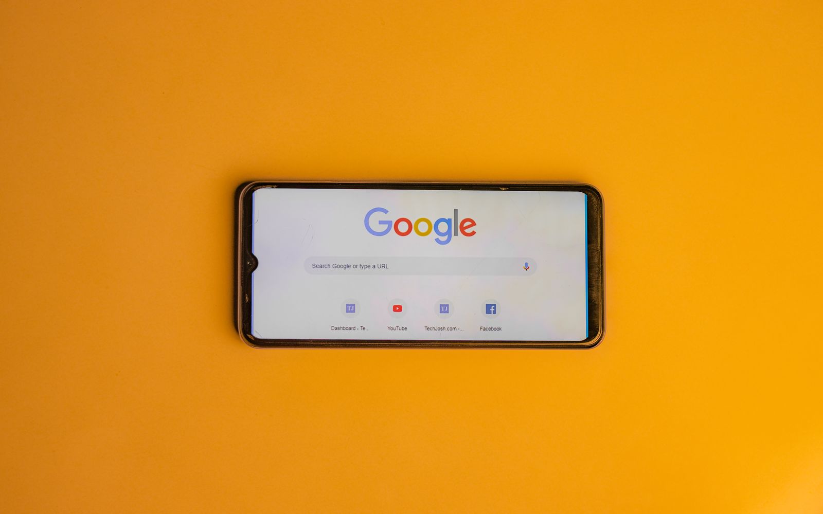 Celular com a página de busca do Google sobre fundo amarelo