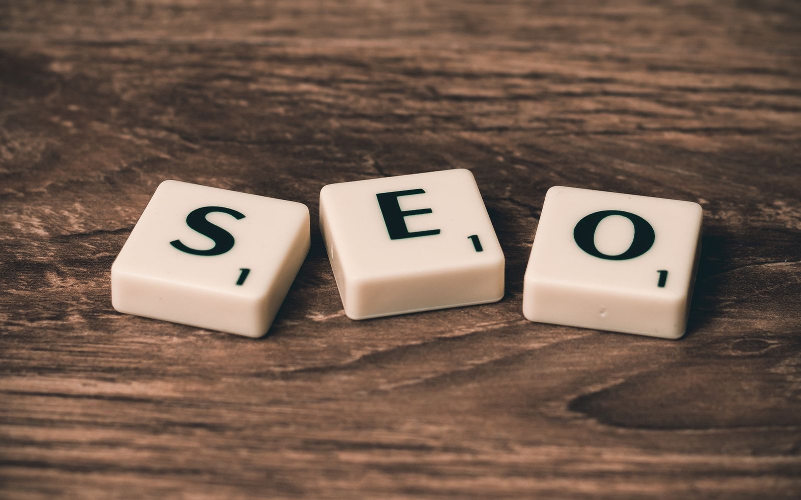 Peças de jogo formando a palavra SEO sobre madeira