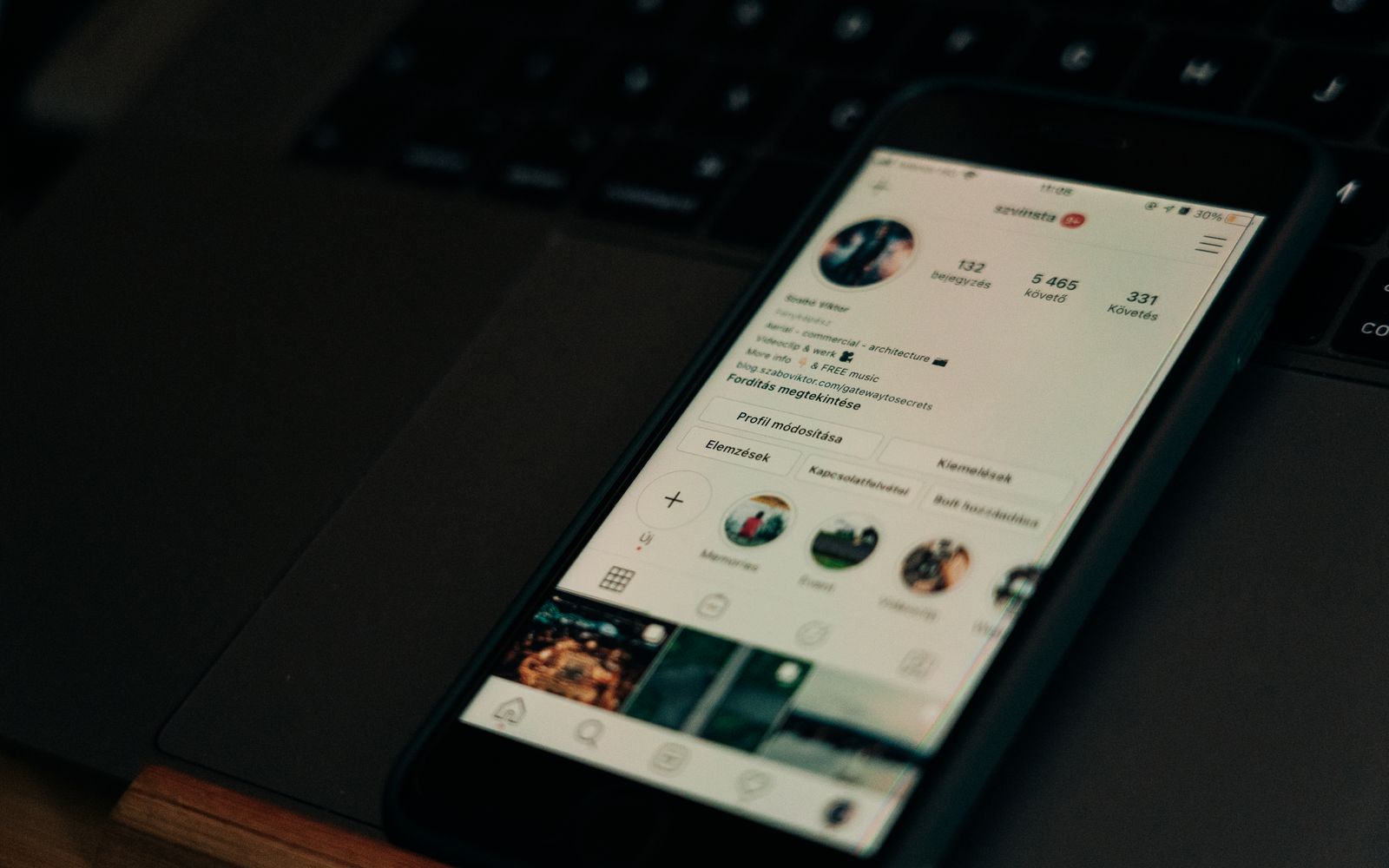Celular exibindo um perfil de rede social ao lado de um notebook