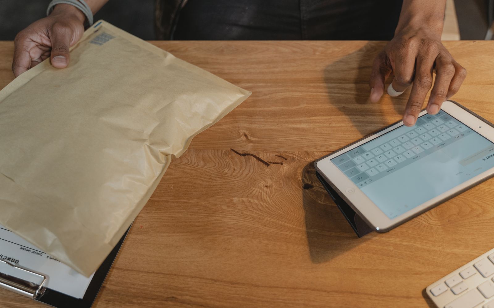 Pessoa conferindo a logística em um tablet, com uma encomenda sobre a mesa