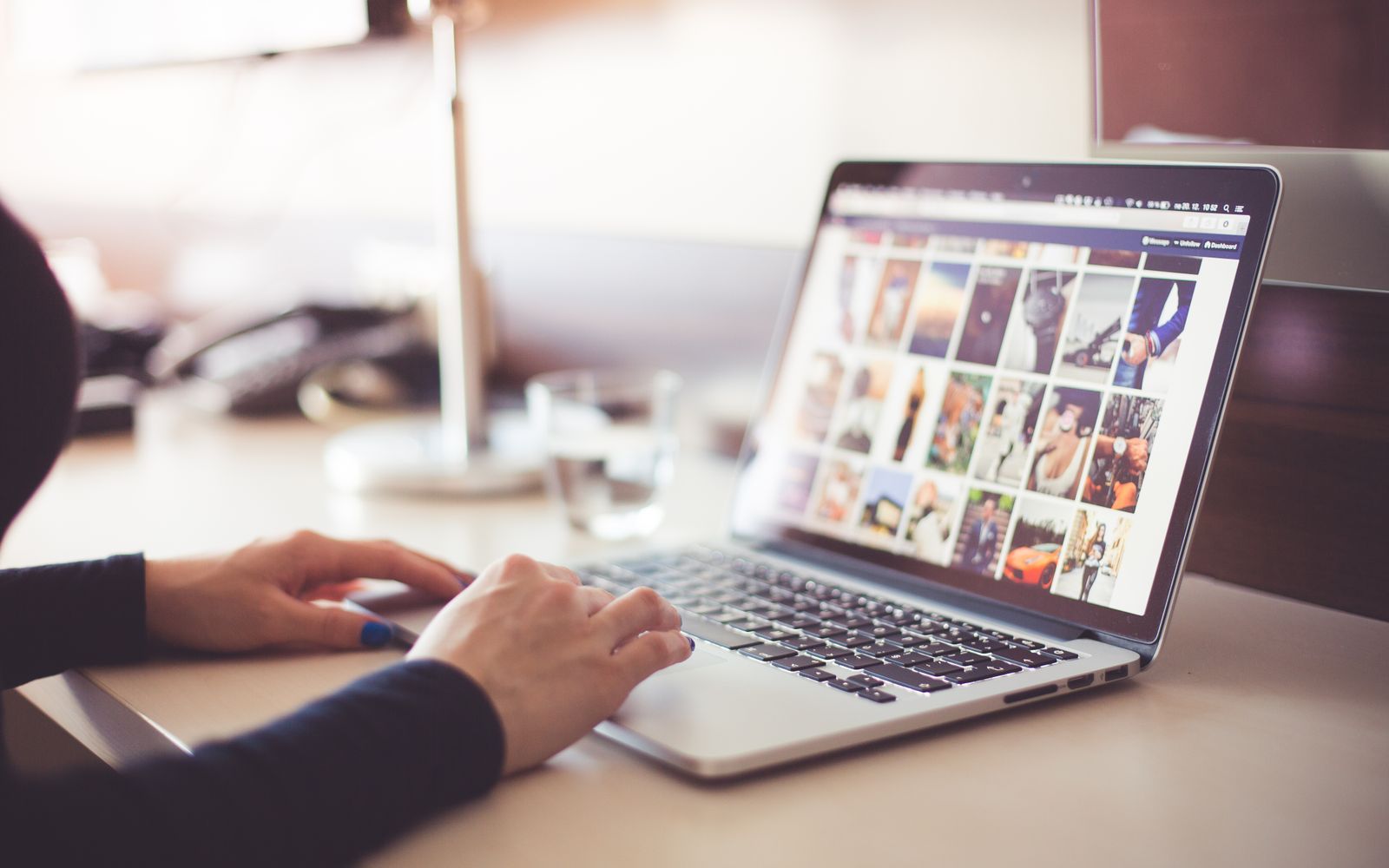Mãos digitando no notebook com uma galeria de imagens aberta