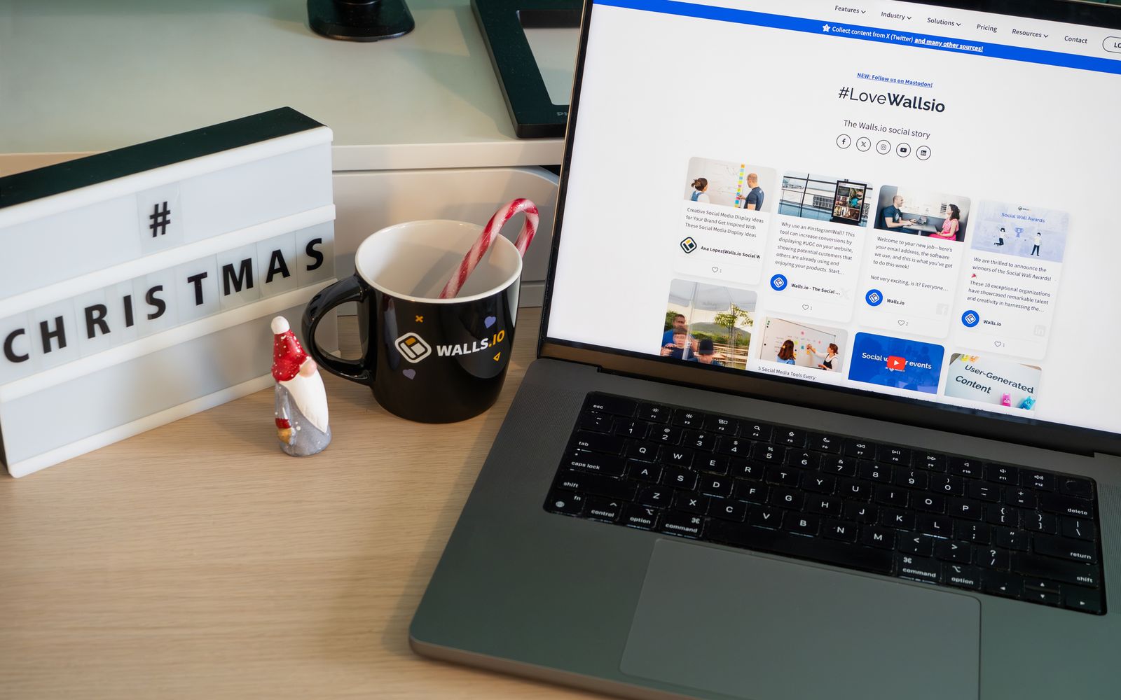 Mesa de escritório com decoração de Natal, caneca e um site aberto no notebook