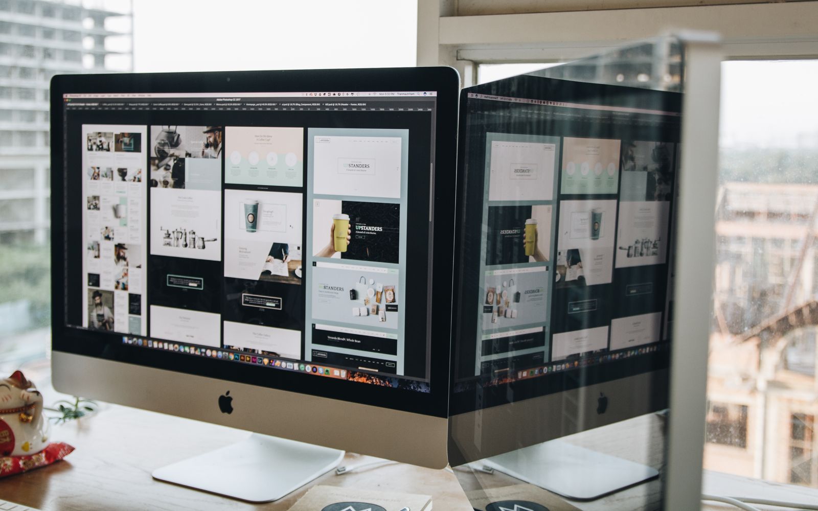 Dois monitores sobre a mesa exibindo trabalho de web design