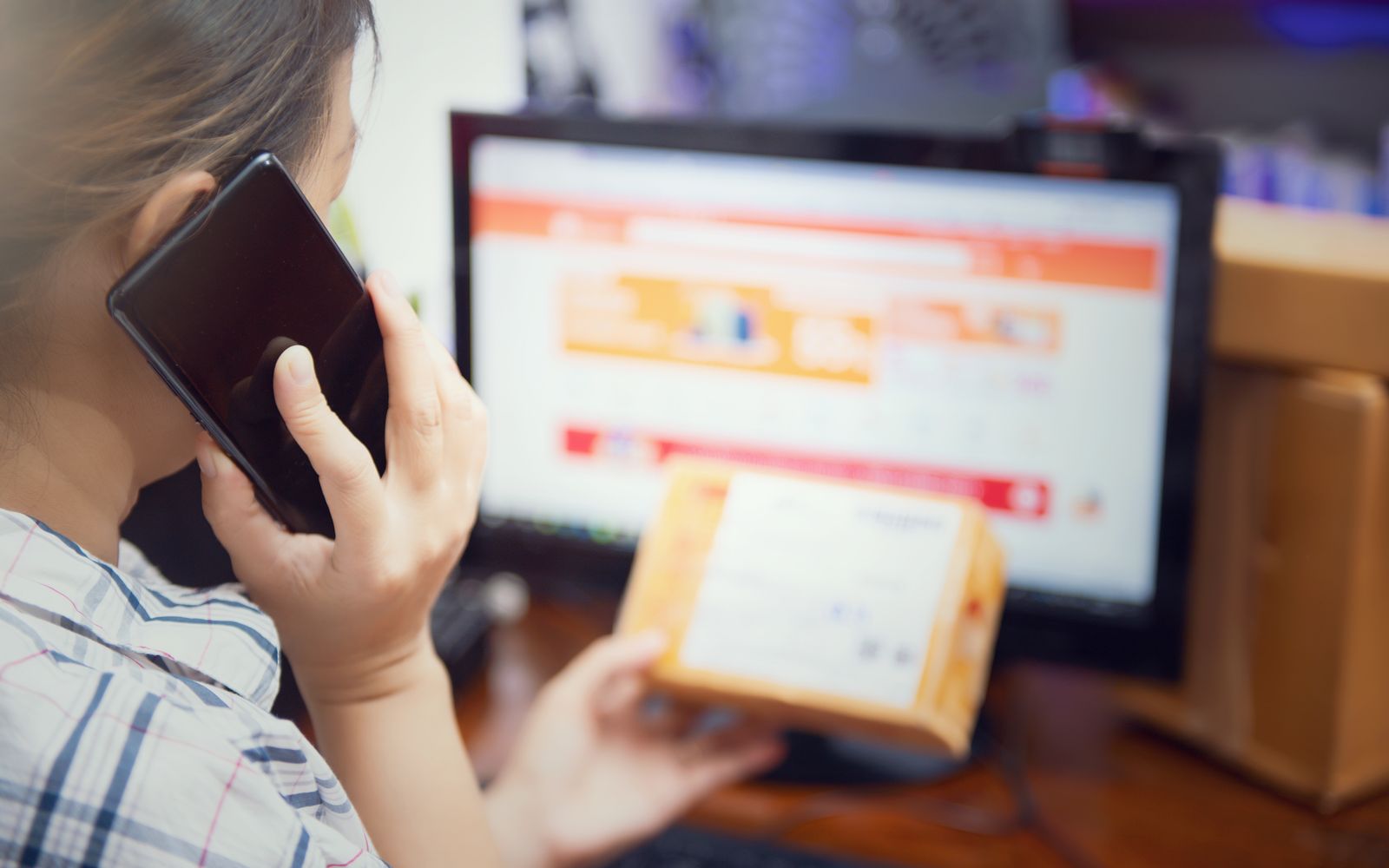 Mulher ao telefone conferindo a embalagem de uma compra online