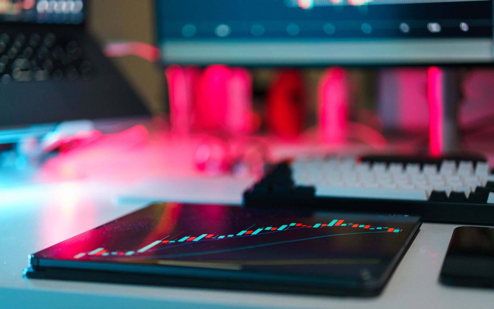 Mesa com gráficos de mercado em tablet e telas de computador