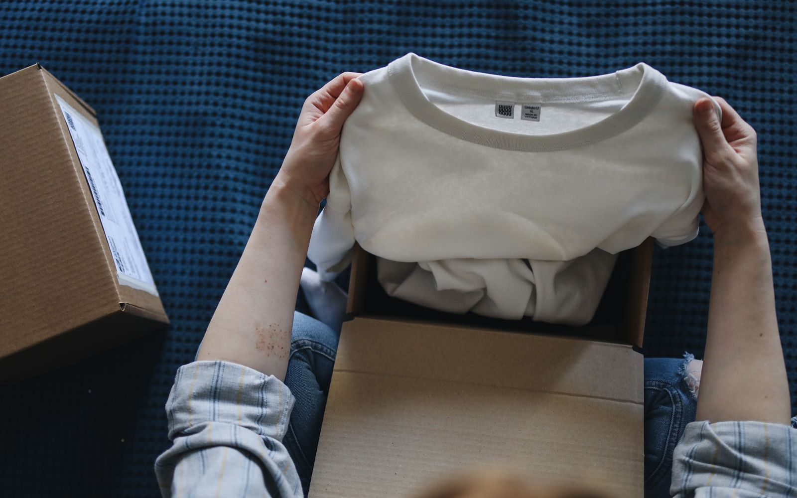 Mãos abrindo uma embalagem com uma camiseta branca nova