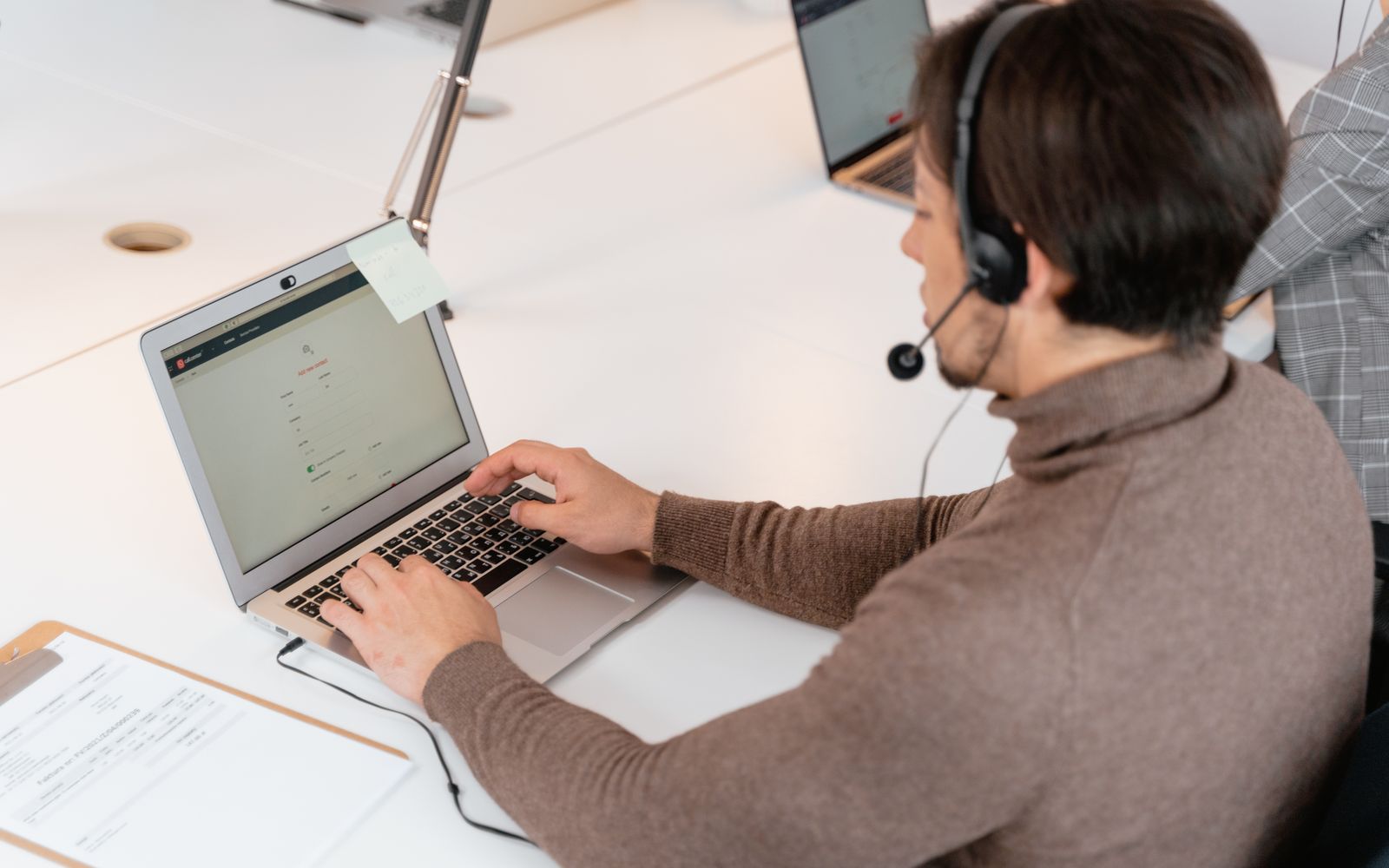 Atendente de central de atendimento usando fone de ouvido trabalhando em um laptop em um ambiente de escritório moderno