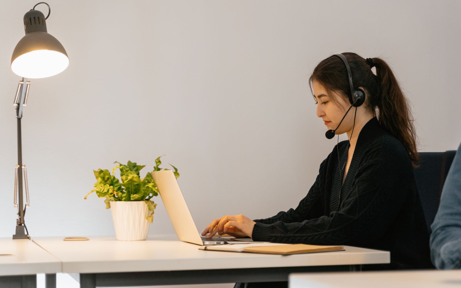 Profissional mulher em trabalho remoto usando laptop com fone de ouvido em escritório moderno