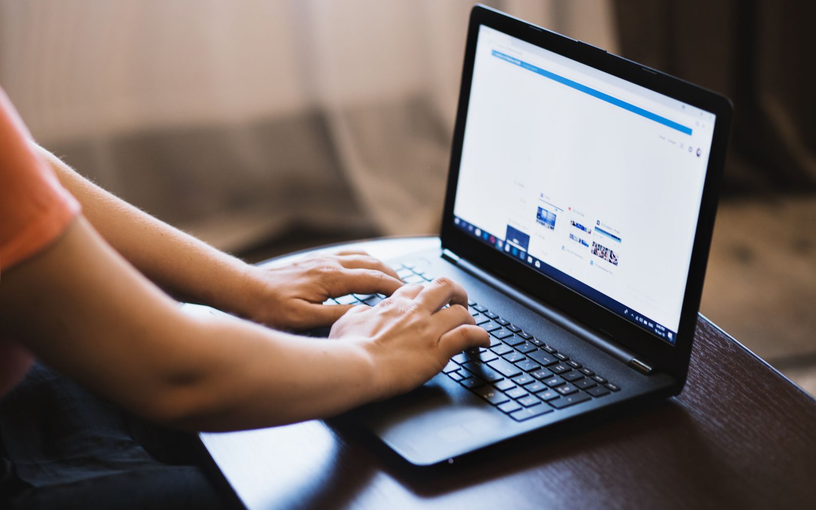 Pessoa digitando em um laptop dentro de um ambiente fechado, mostrando o uso de tecnologia