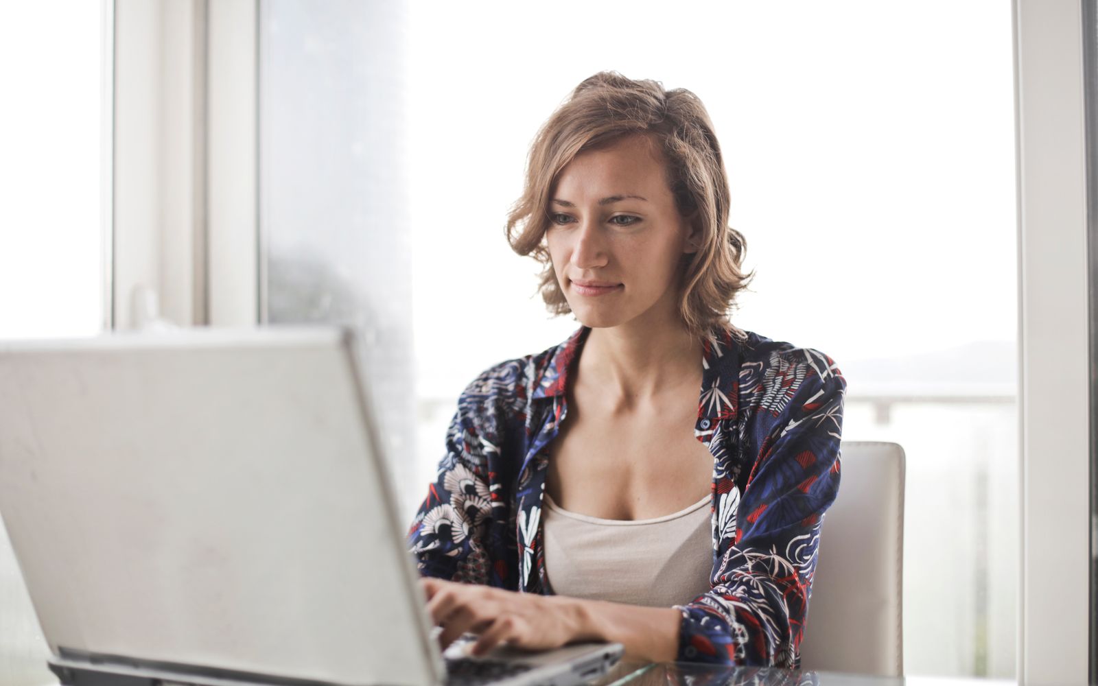 Uma mulher digitando em um laptop em um escritório doméstico moderno e bem iluminado