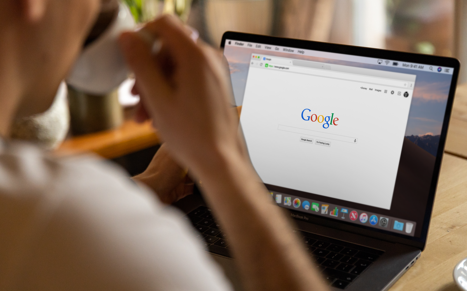Adulto tomando café enquanto navega no Google pelo notebook