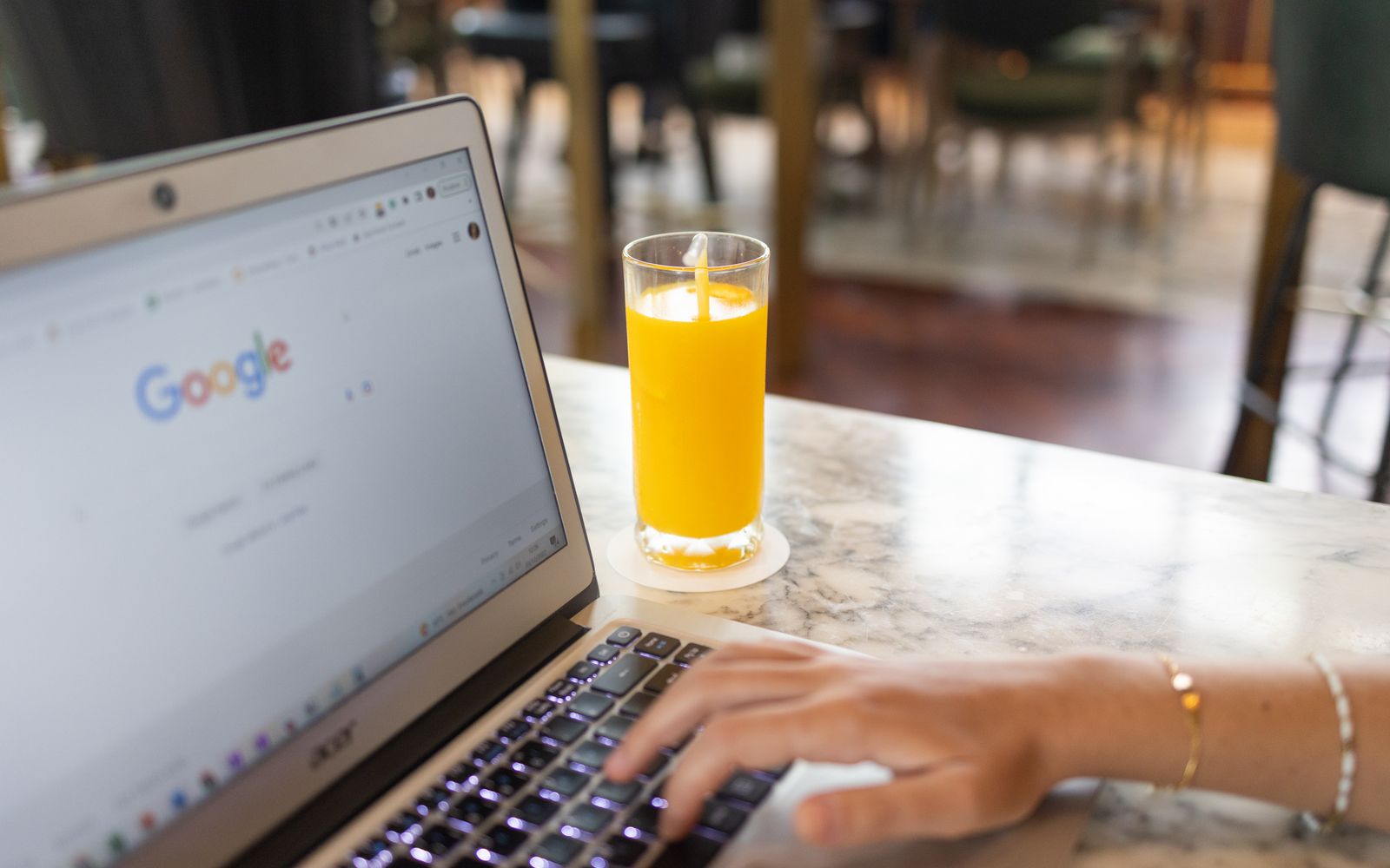 Mulher digitando no notebook com a página do Google aberta
