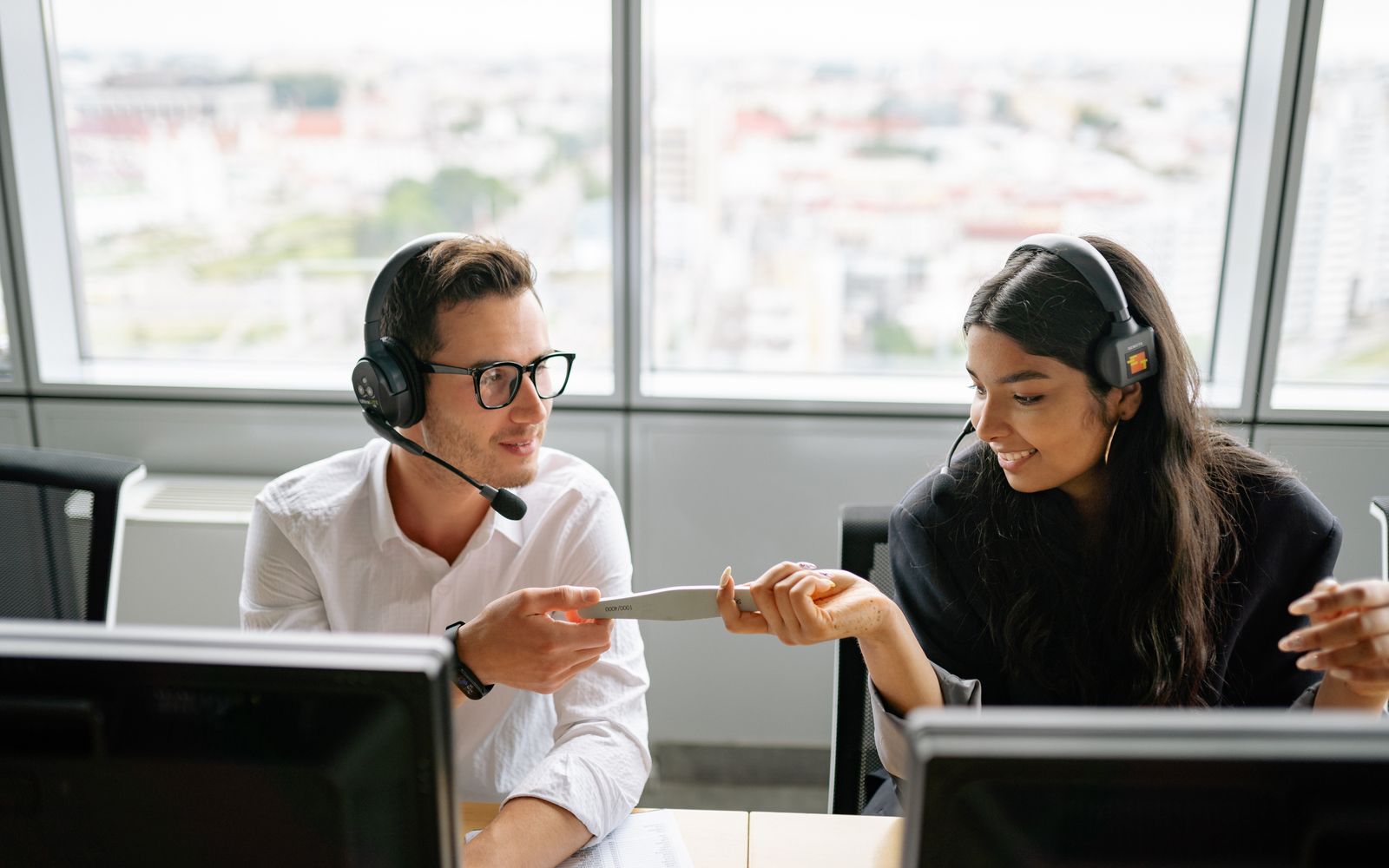 Dois atendentes conferindo um documento enquanto falam com clientes