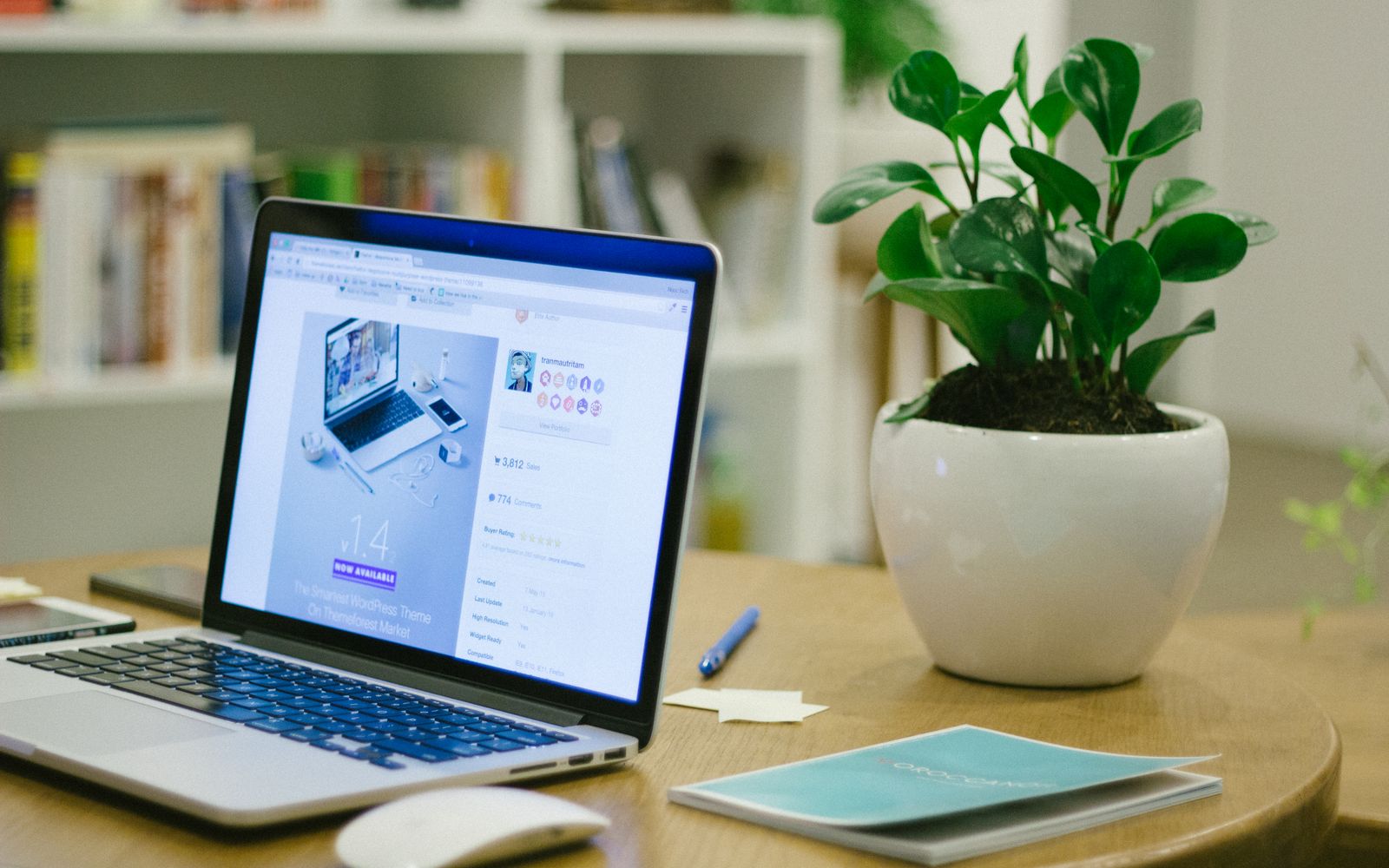 Um ambiente de trabalho moderno com um laptop e uma planta em vaso sobre uma mesa, oferecendo um cenário fresco e organizado