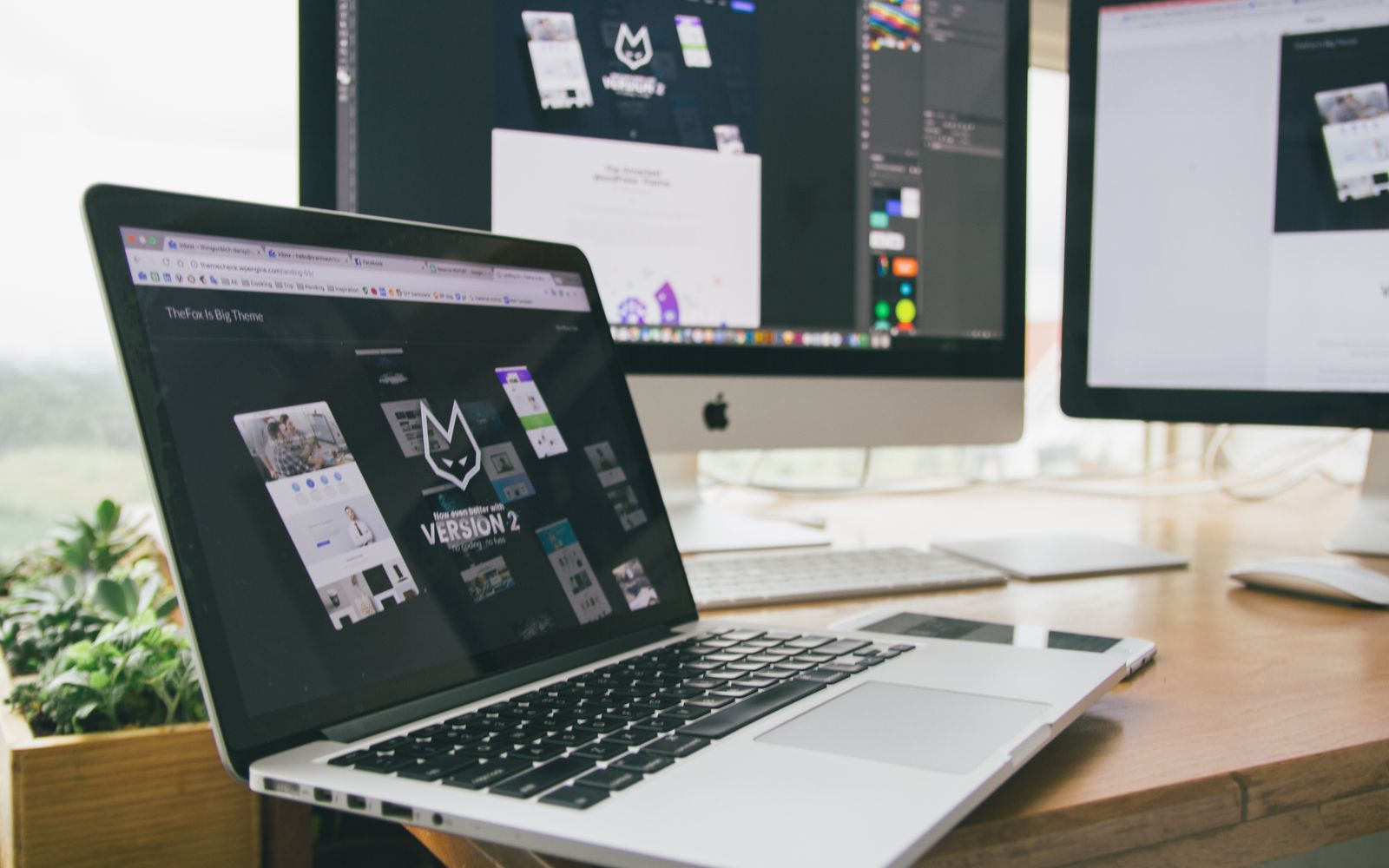 Mesa de trabalho com notebook e monitores exibindo software de design