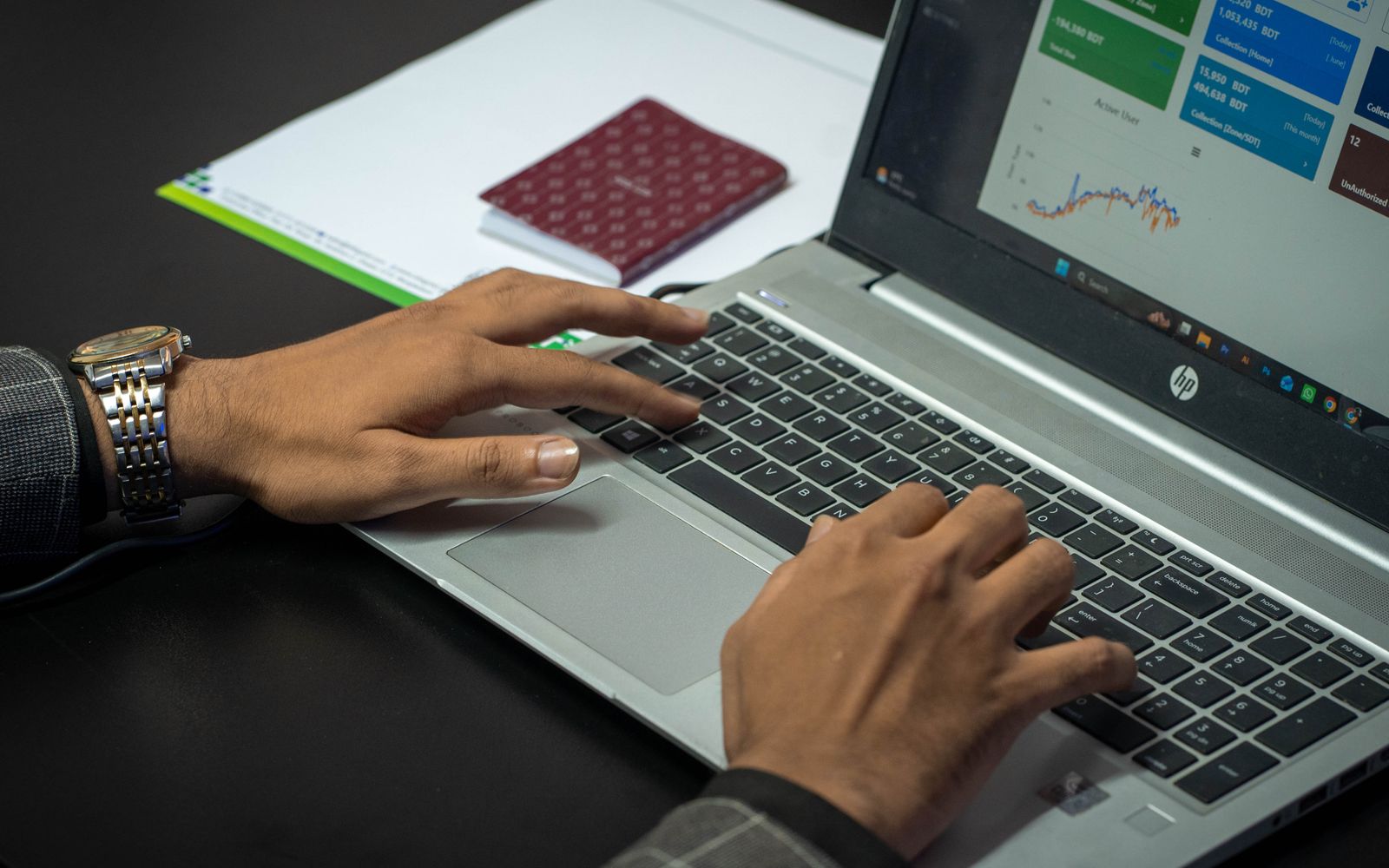 Mãos no teclado do notebook com um painel de indicadores na tela
