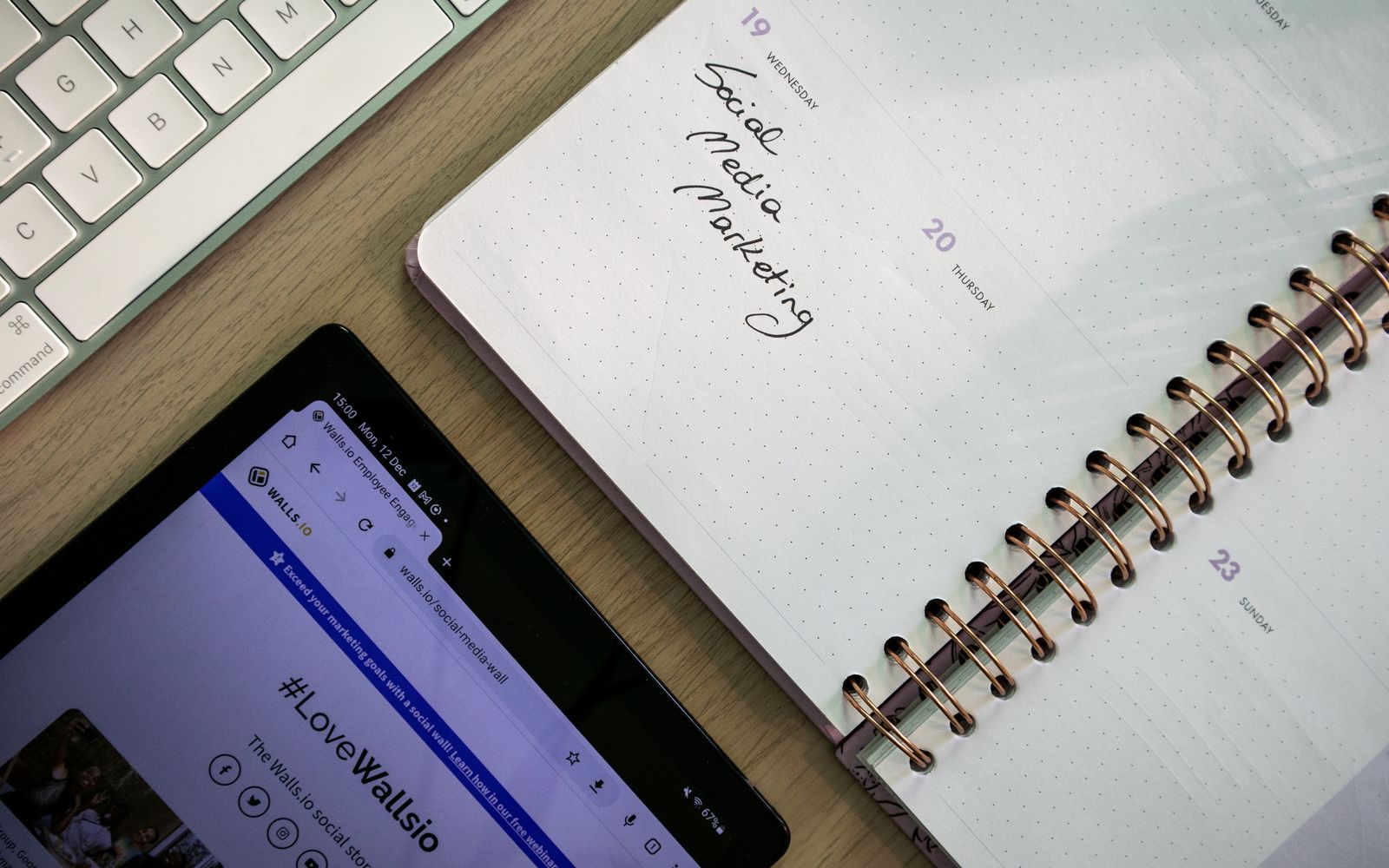 Visão superior de um caderno, tablet e teclado usados para planejamento de marketing nas redes sociais