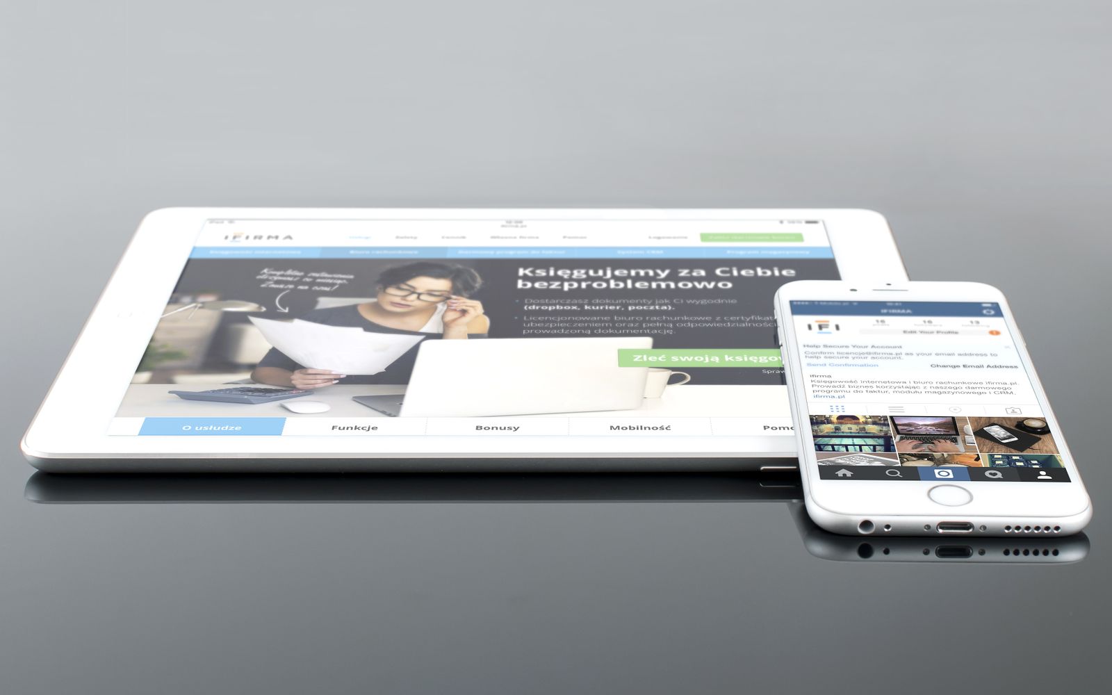 Tablet e celular exibindo conteúdo web sobre superfície reflexiva