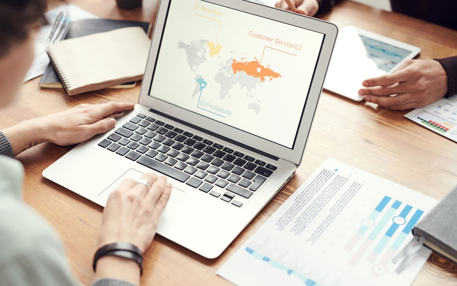 Equipe profissional discutindo estratégias de marketing global com gráficos e tabelas em um laptop